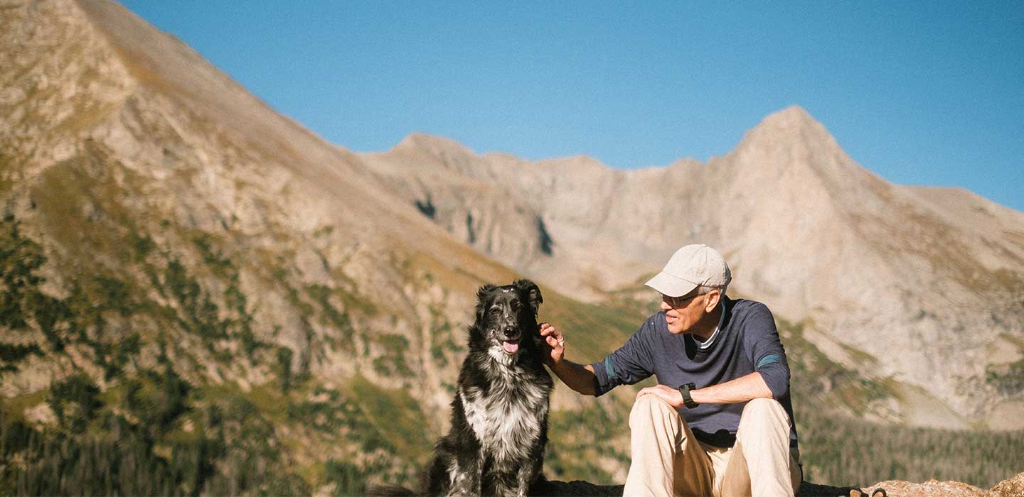older man and dog at the mountains