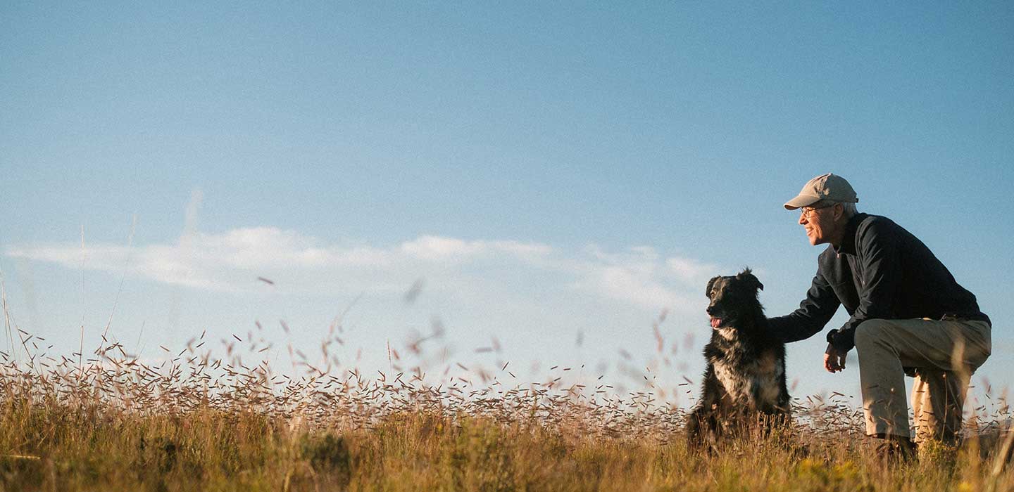 older man and dog in a field